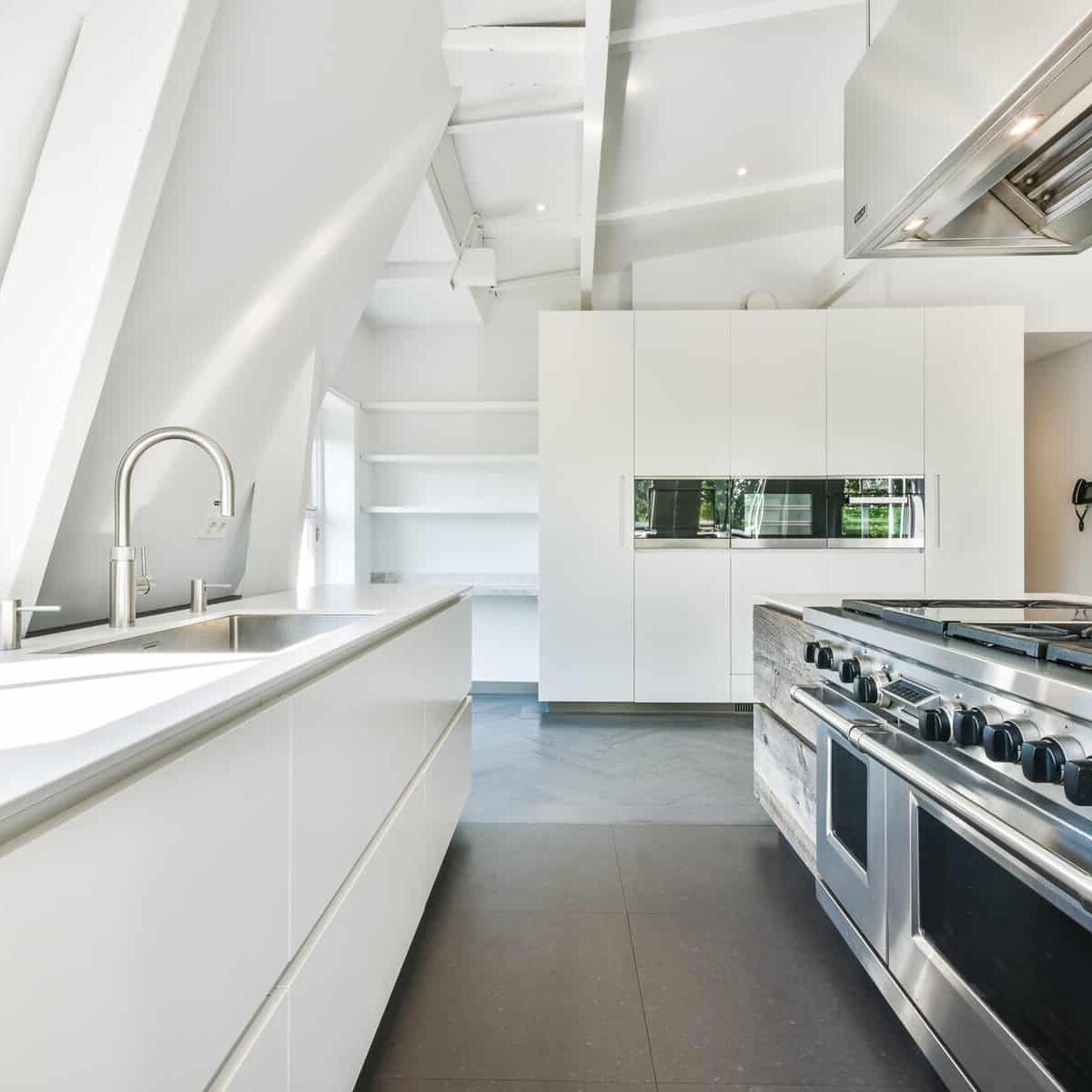 Interior of contemporary kitchen with white furniture and shiny appliances in flat
